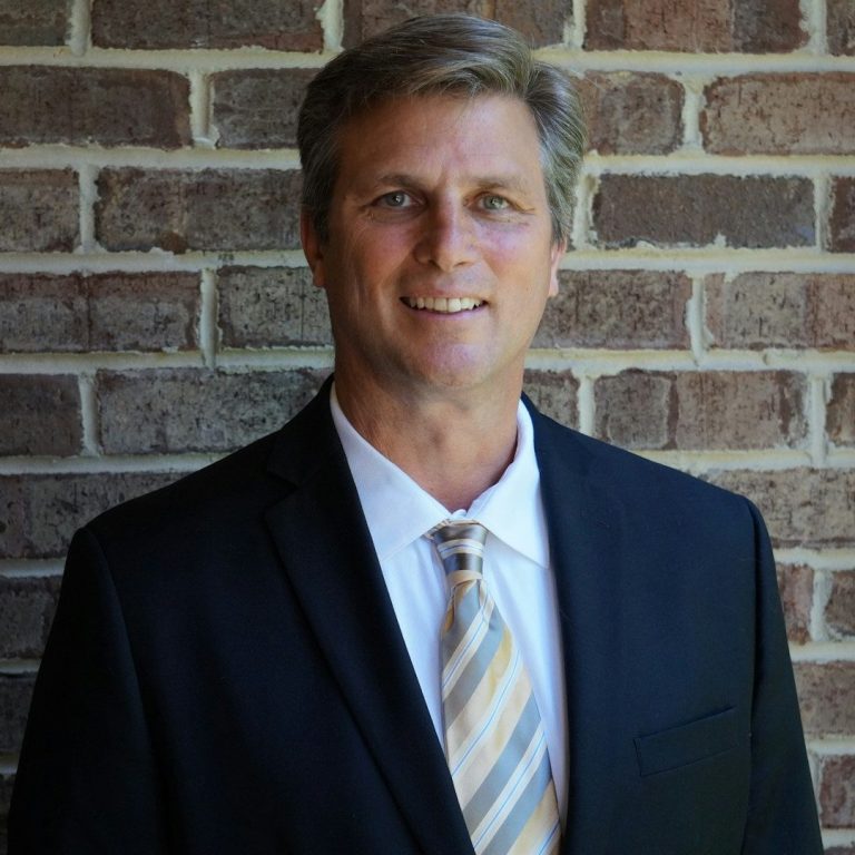 CEO Kunde für Kinderzaubershow Mann in Anzug mit Krawatte steht vor einer Backsteinmauer.